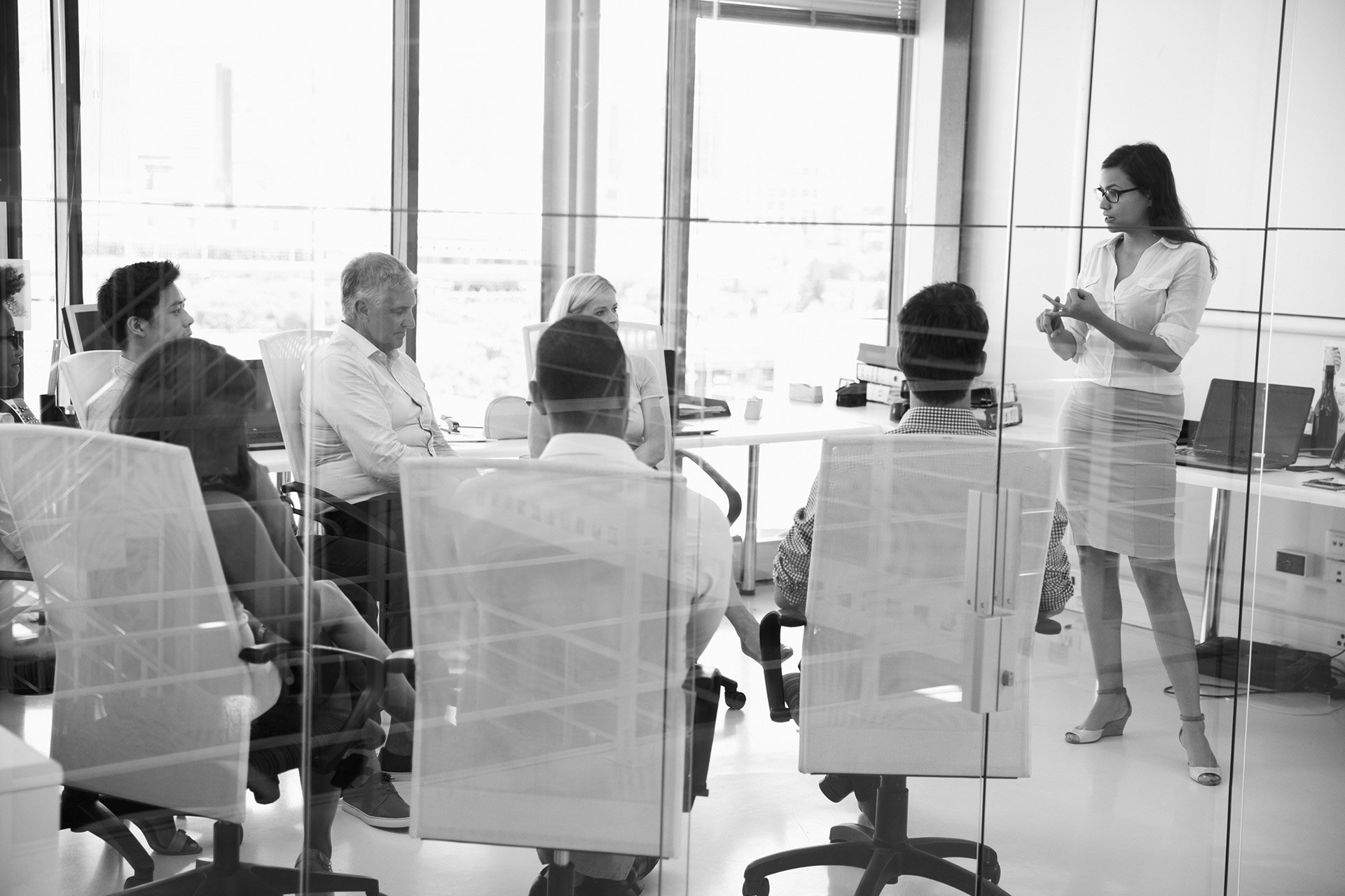 Woman standing in a board room presenting to a group in a meeting about value creation